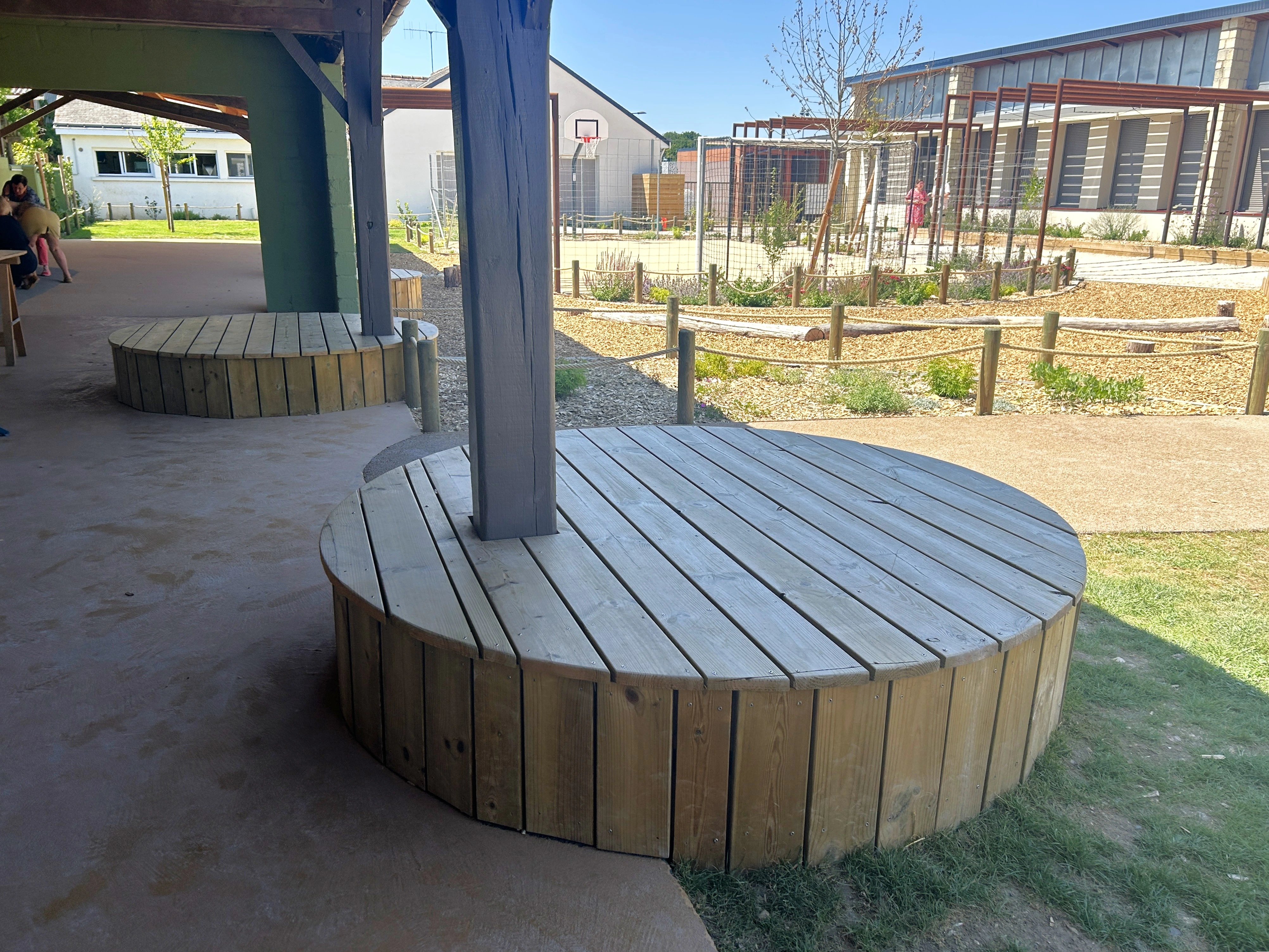 Assises circulaires en bois sous le préau de l’école La Clochette